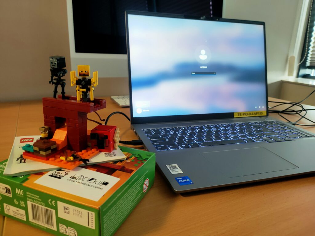 Laptop na biurku, obok złożona figurka z klocków konstrkcyjnych